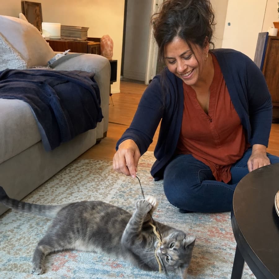 Candid photo of Iyari Santillán playing with her cat on the floor